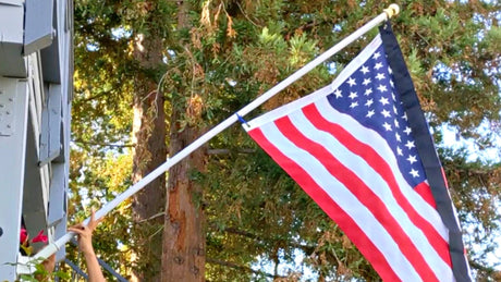 American flag on mounted pole with a mourning half-staff streamer