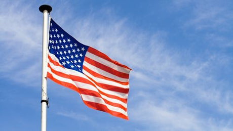 An American flag flying on a flagpole under a blue sky