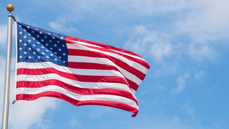 An American flag flying on a flagpole under a blue sky
