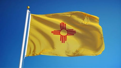 New Mexico state flag flying outside on a flagpole.