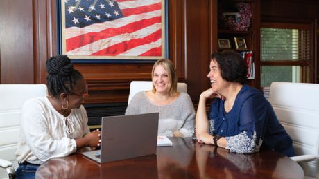The Flags USA team working at a table with an American flag portrait hanging on the wall.