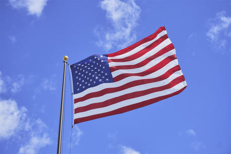 American flag flying in the wind on a blue sky day