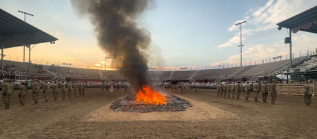 Utah National Guard soldiers, American Legion members, and Boy Scouts at a flag retirement ceremony fire at dusk.