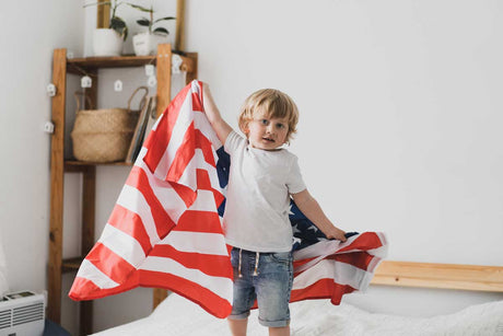 A young boy holding an American flag inside a living room
