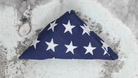 Folded American flag in triangle shape with stars visible on blue field