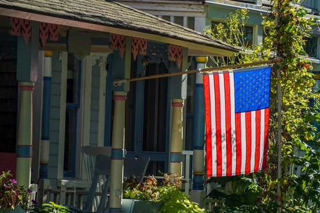 American flag displayed outside of a home with a flag pole.