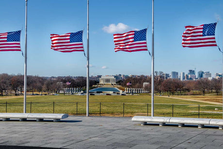Four American flags flying half-staff on separate flag poles