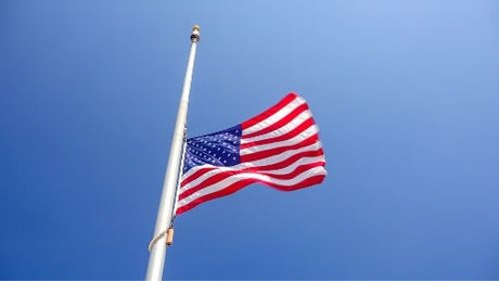 An American flag flying at half-staff on a flagpole