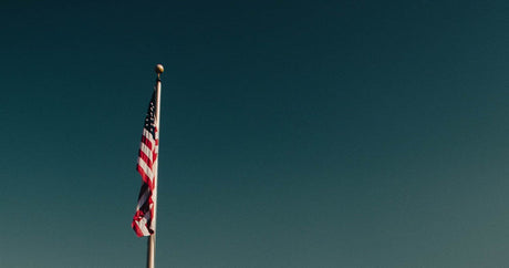 American flag flying at full staff on a flagpole against a late-summer sky